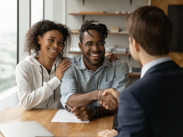 Man shaking hands with person across desk
