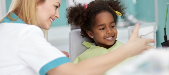 Dental assistant showing a child patient their smile in a mirror