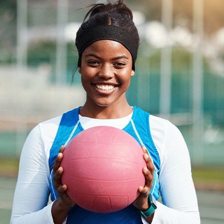 Teen girl smiling while holding basketball